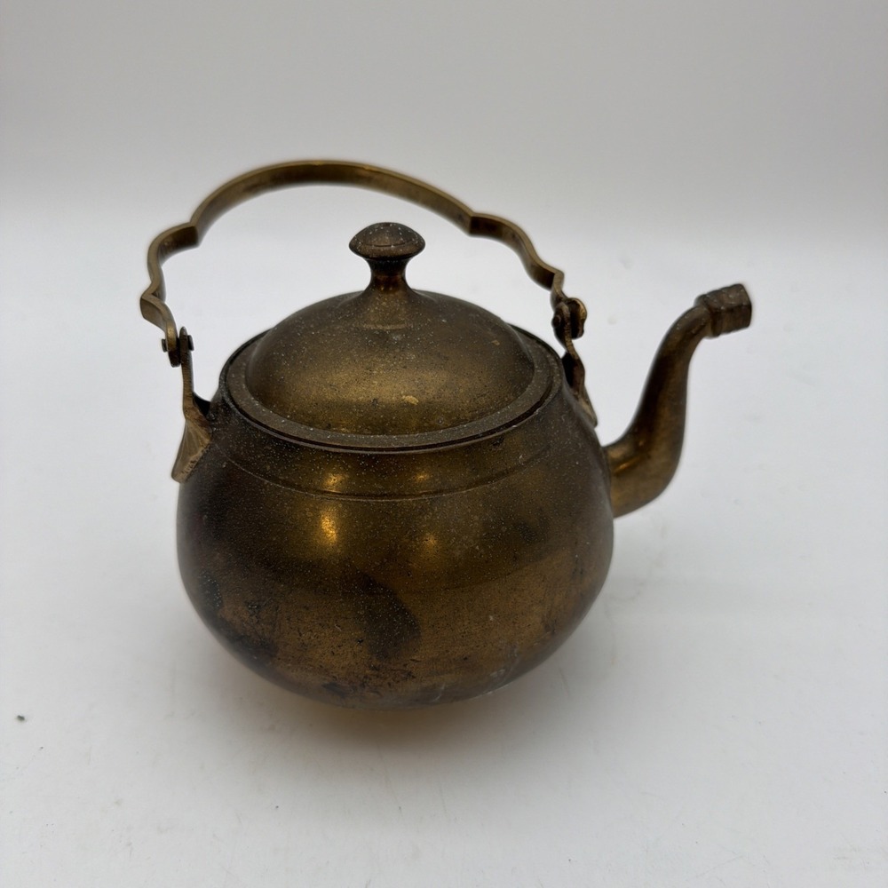 vintage, unbranded brass teapot with a rounded body, a curved swing handle